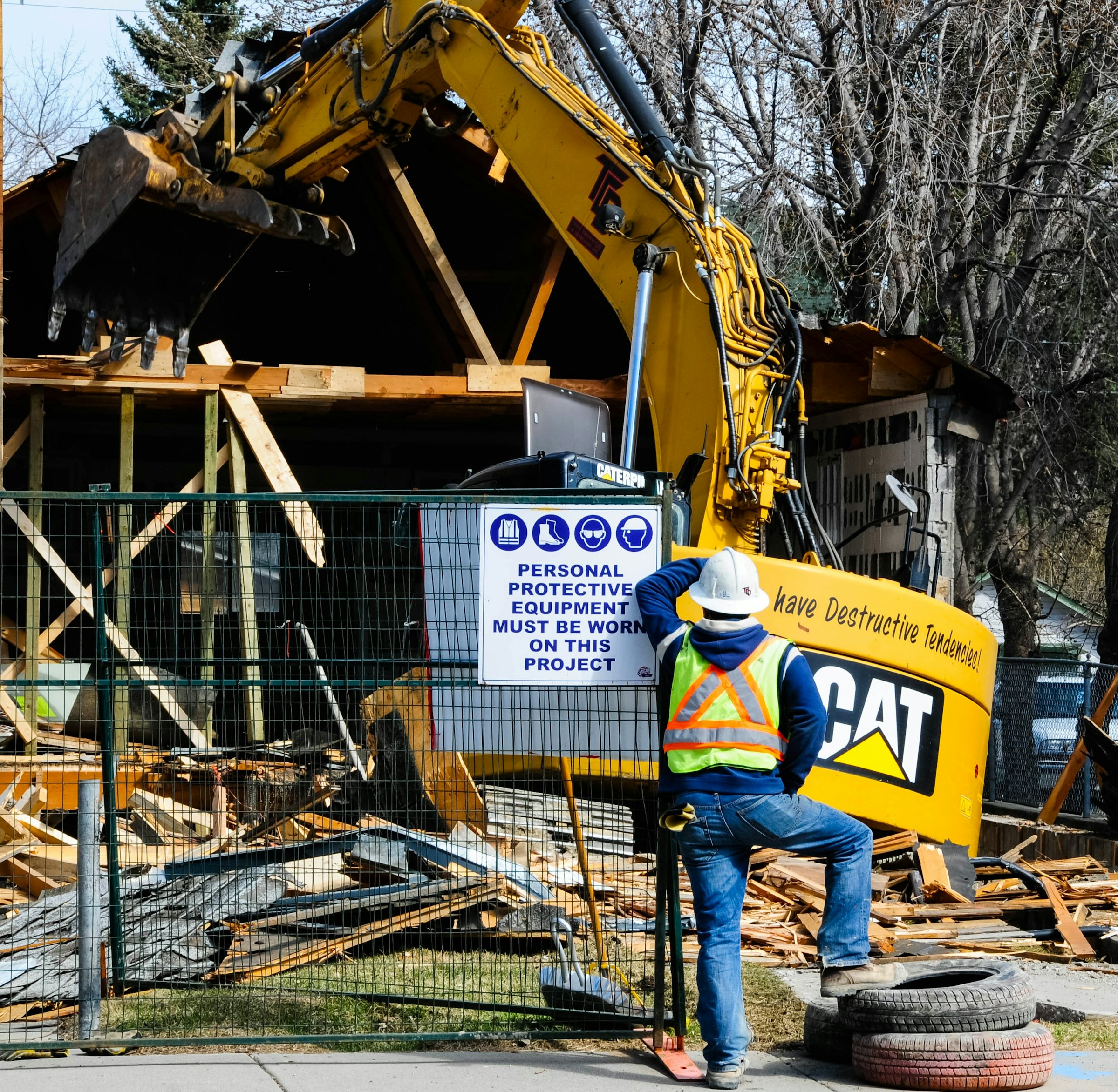 A crew member watching an excavator demolish a house